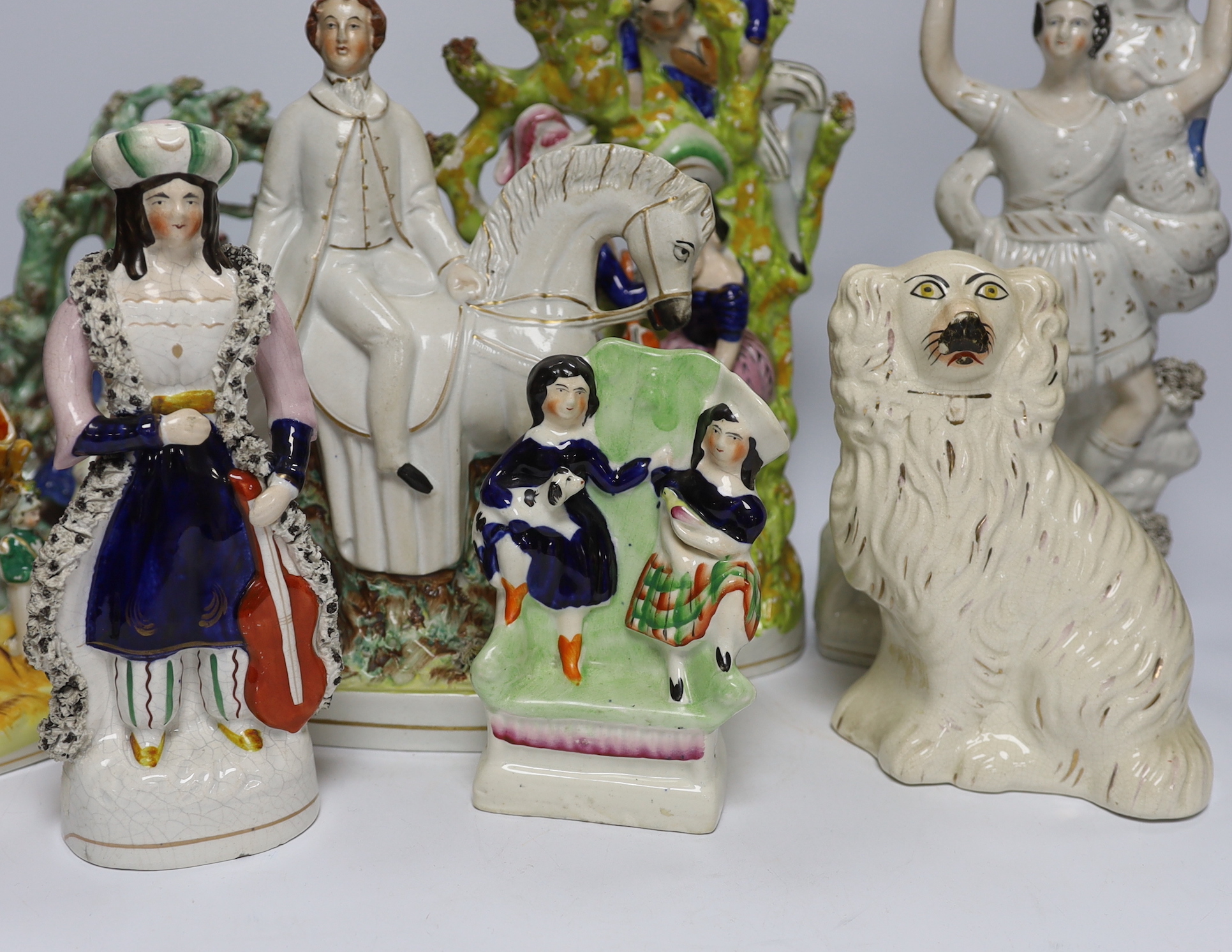 Seven Staffordshire flat backs, including a gentleman on horse back, two seated lovers, a similar pair of King Charles Spaniels, and a pair of Staffordshire style cats, tallest 32cm